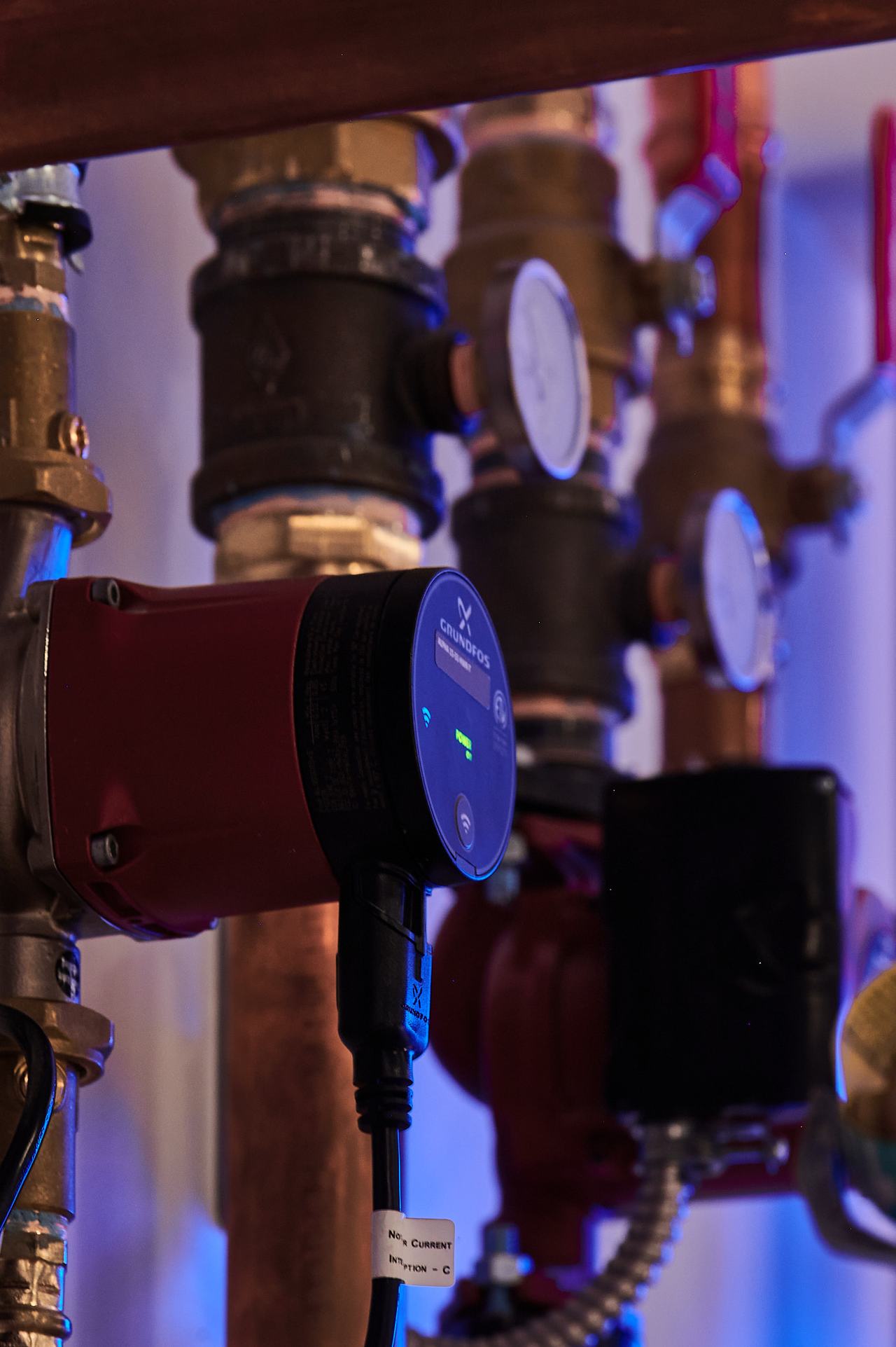 Close-up of a hydronic circulator pump and gauges in a residential heating system