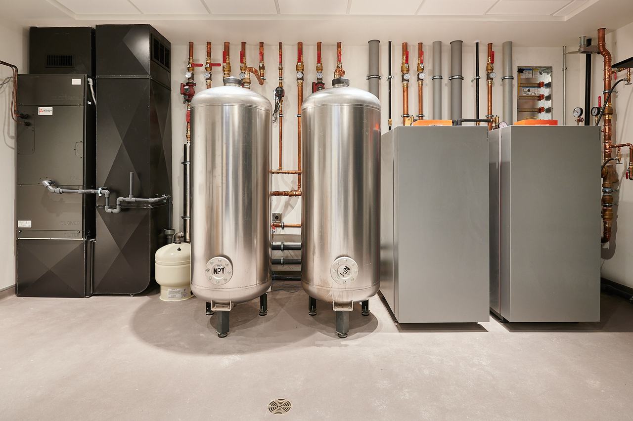 Residential mechanical room in Qualicum Beach with stainless storage tanks and boilers installed by Waywest