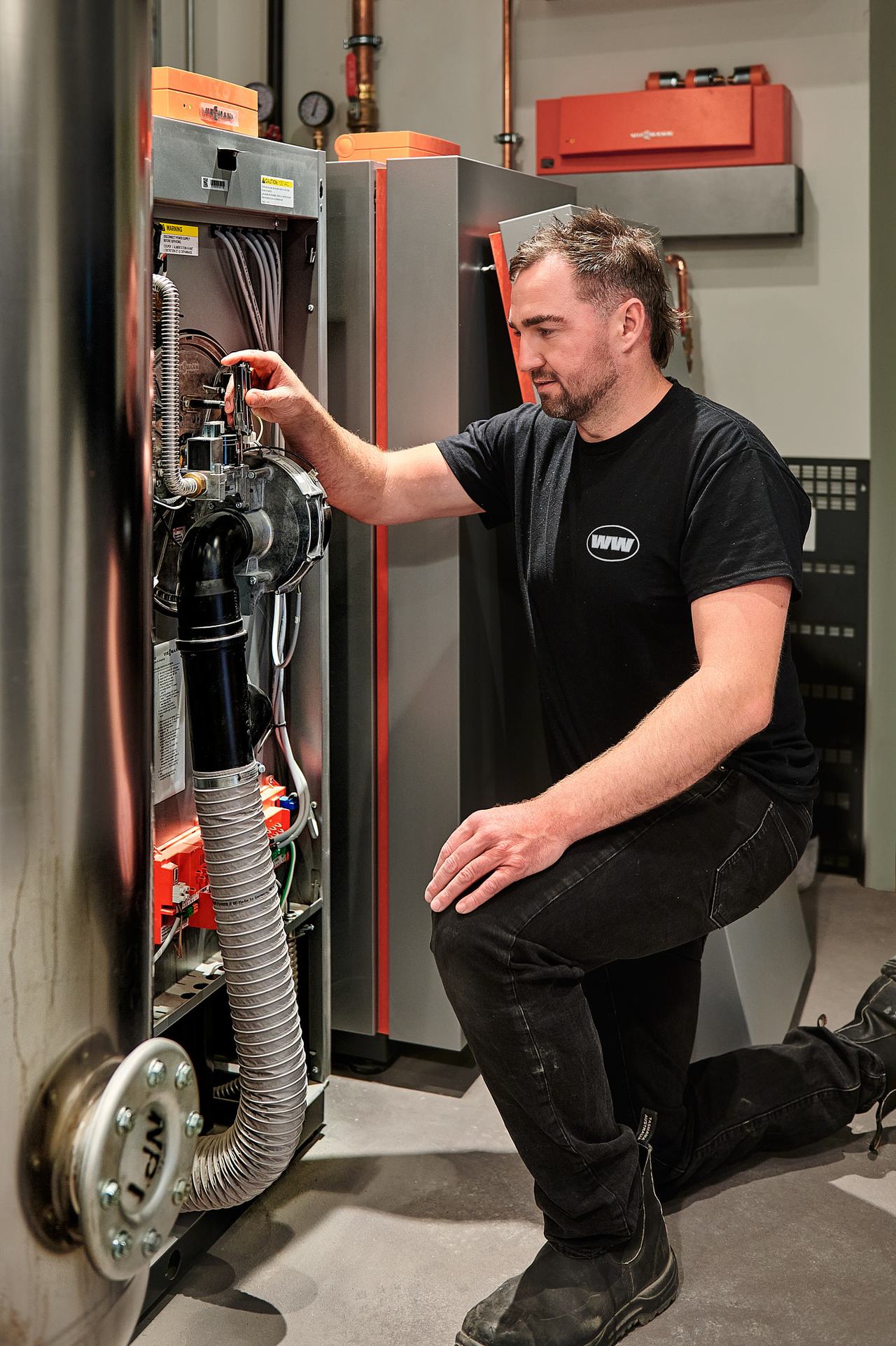 Waywest technician checking boiler connections in a Qualicum Beach mechanical room