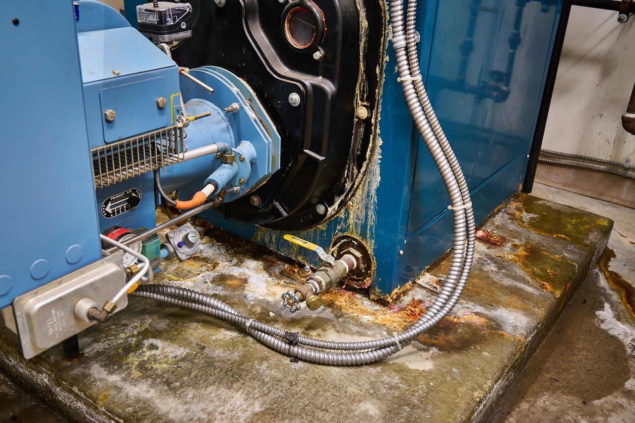 Corrosion and water damage at the base of an old commercial boiler
