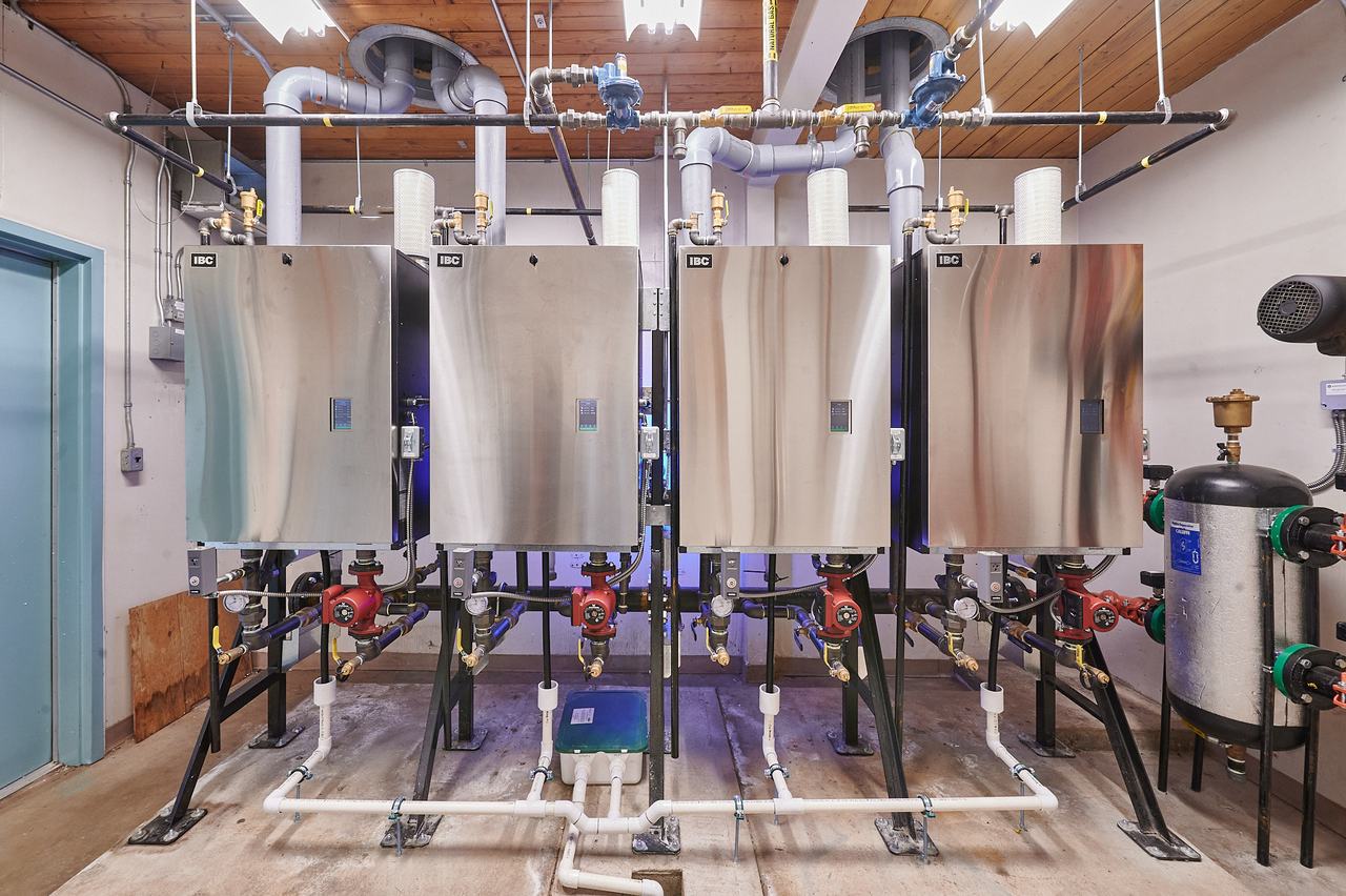 Bank of new high-efficiency boilers installed by Waywest in a commercial mechanical room on Latimer Road