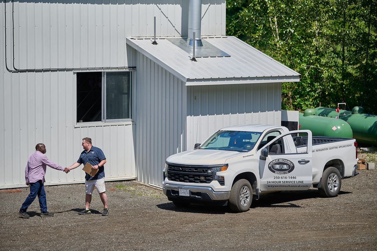 Waywest technician shaking hands with a client beside a Waywest 24-hour service truck in Nanaimo