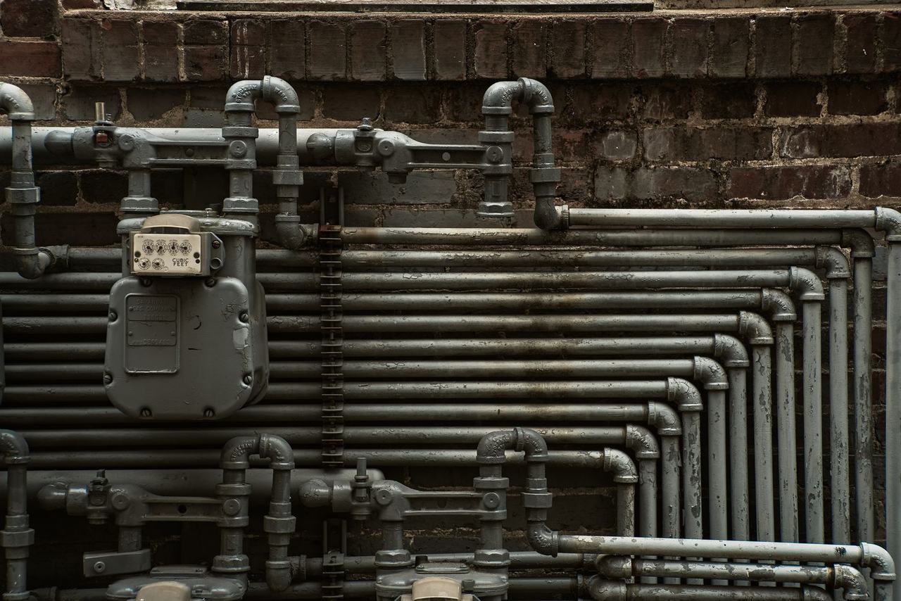 Steel gas piping and a gas meter on a brick wall