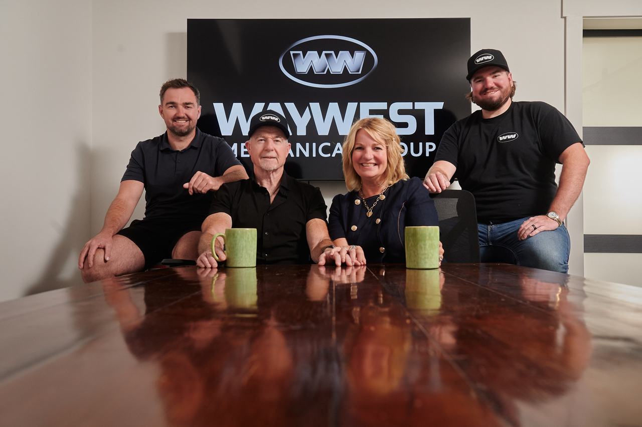 Waywest Mechanical Group team seated in front of the company sign in Nanaimo