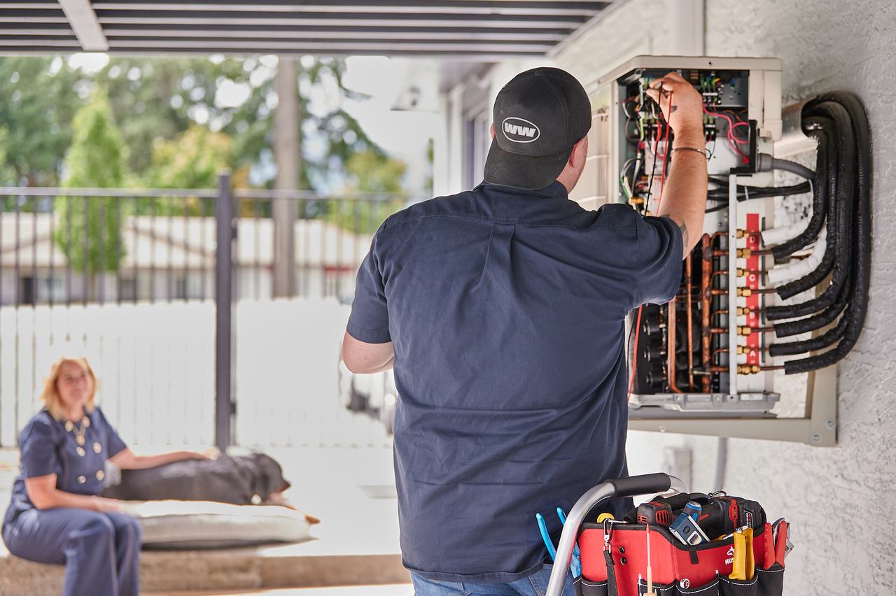 Waywest technician working on a wall-mounted PEX manifold at a Nanaimo home