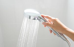 A hand holding a shower head with water coming out of it.