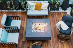 Overhead view of a burning outdoor gas fireplace, acting as a patio heater, surrounded by 5 cozy chairs. Just one example of an outdoor heating solution that WayWest Mechanical can help install or service.