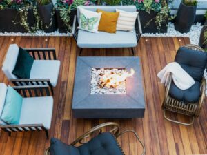 Overhead view of an outdoor gas fireplace burning on a patio, surrounded by 5 cozy chairs.